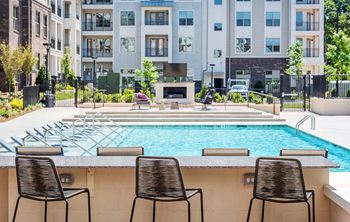 Three chairs are lined up by a pool.